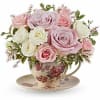 Pink and white roses arranged in a floral teacup