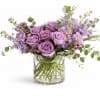 Lavender roses and purple flowers in a clear glass vase