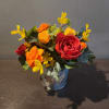 Small arrangement of red, orange, and yellow flowers in a metal pot