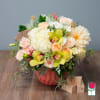 Mixed bouquet in a coral vase with pale roses and yellow orchids