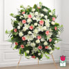 Large standing funeral spray with white and pink flowers on an easel