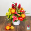 Tropical flower arrangement in a white vase with red and yellow blooms