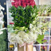 Tall arrangement of red roses and white hydrangeas in a gold hat box with pink ribbon