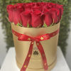 Round box of tightly packed red roses in a gold hatbox with a red ribbon bow