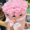 Pink hat box filled with tightly packed light pink roses and tied with a matching ribbon