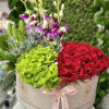 Round hatbox arrangement with red roses, green hydrangeas, and purple orchids tied with a pink ribbon.