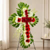 Cross-shaped floral standing tribute with red roses, white blooms, and green leaves