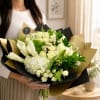 Bouquet of white roses, calla lilies, and hydrangeas wrapped in black and gold paper