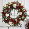 Circular funeral wreath of red and white roses on a stand