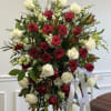 Standing spray of red and white roses with ribbon on an easel