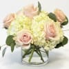 Blush roses and pale hydrangeas in a clear glass vase