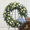 Large floral wreath with white and blue flowers on a stand