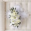 White floral cross with lace trim and ribbon on a tufted cream cushion