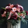 Pink and burgundy floral arrangement with ribbon on a pedestal