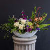 White roses and purple flowers in a white bowl vase