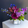 Colorful bouquet in a speckled square vase with purple and blue flowers