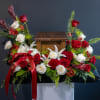 Red and white roses arranged around a wooden urn with a red ribbon