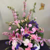 Pink lilies and carnations arranged with purple filler flowers