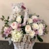 White wicker basket with pastel roses, orchids, and a plush cat