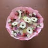 Pink-wrapped bouquet of white gerbera daisies and mixed pastel flowers