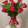 Bouquet of red roses in a glass vase with a pink ribbon