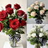 Bouquets of red, blush, and white roses in glass vases with striped ribbons