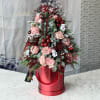 Pink roses and holiday greenery arranged in a red hatbox with ribbon and teddy bear picks