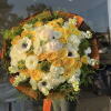 Large bouquet of yellow and white flowers wrapped in orange paper