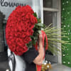 Large bouquet of red roses with long stems and a red ribbon