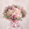 Large round bouquet of pale pink and white roses and hydrangeas with pink orchids, wrapped in pink paper and ribbon