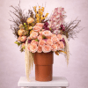 Tall arrangement of peach roses, ranunculus, orchids, and yellow berries in a brown vase on a white pedestal.