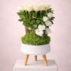 White roses arranged in a small white planter on a stand