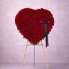 Heart-shaped standing arrangement of red roses on a wooden easel with a black ribbon bow.