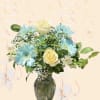 Blue daisies and cream roses arranged in a glass vase