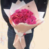 Bouquet of bright pink roses wrapped in pale paper