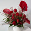 Red anthuriums and tulips arranged in a white vase