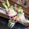 Bouquet of lilies, roses, and purple mums in a glass vase