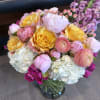 A bright, romantic bouquet of mixed-color roses, ranunculus, hydrangeas and peony-like blooms