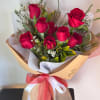 Bouquet of red roses wrapped in brown paper with a red and white ribbon