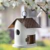 White hanging birdhouse with a brown roof and small round entrance