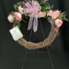 Pink floral wreath with a ribbon bow on a twig base