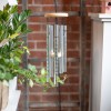 Hanging silver wind chime with a wooden top and black cords