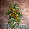 Tall floral standing spray with sunflowers and white blooms on an easel