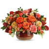 Orange roses and mixed fall flowers arranged in a brown vase