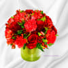 Red roses and mixed red flowers arranged in a green vase