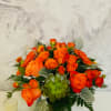 Orange rose arrangement in a glass vase with a green succulent