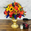 Colorful bouquet of roses, sunflowers, and mixed blooms in a gold vase