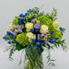 Bouquet of blue, lavender, and white flowers in a clear glass vase