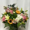 Mixed bouquet of pink roses, lilies, sunflowers, and white hydrangeas in a glass vase
