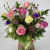 Mixed bouquet of pink, purple, and yellow roses in a glass vase
